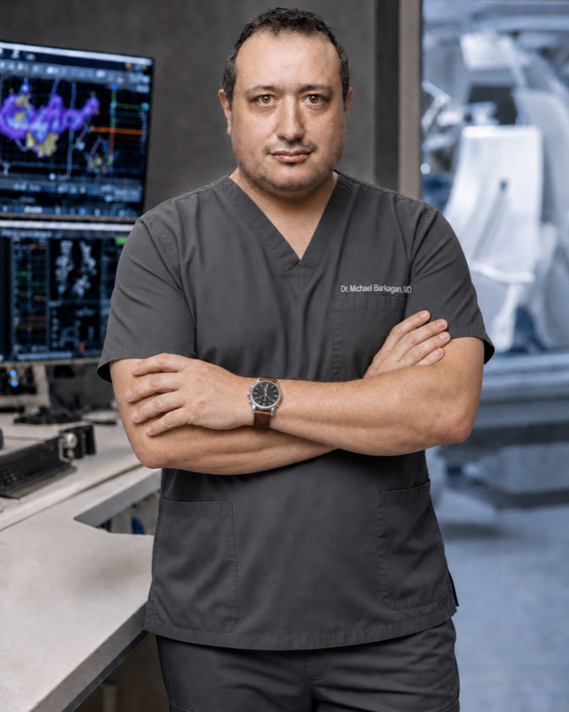 Dr. Michael Barkagan in clinical scrubs, arms crossed, in an electrophysiology laboratory. A digitally generated image, not a photograph.